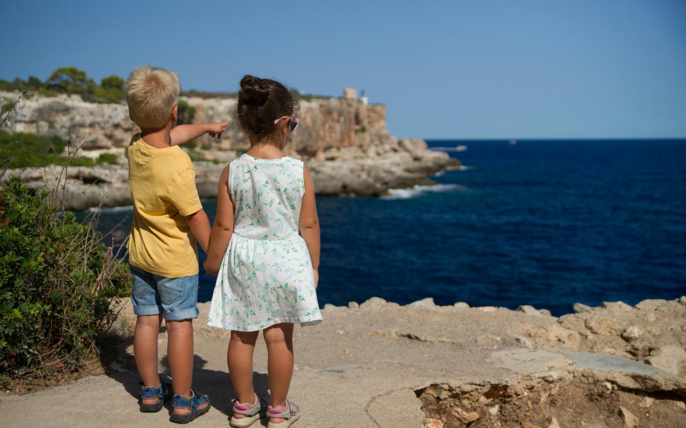 two children standing near cliff watching on ocean at daytime by Torsten Dederichs courtesy of Unsplash.
