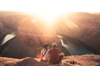 man and woman sitting on rock formation by Christopher Burns courtesy of Unsplash.